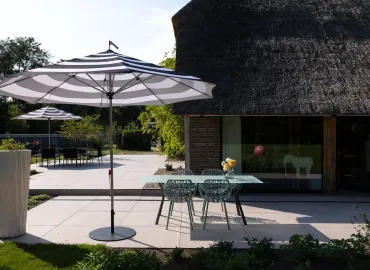 tuin met terras en huis rieten dak